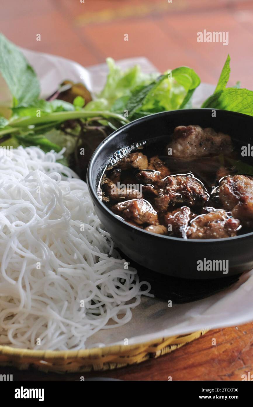 Brötcha nach Hanoi-Art mit gegrilltem Schweinefleisch und Fleischbällchen, Reisnudeln, frischem Salat und Kräutern (Minze, Perillablatt, Koriander) Stockfoto