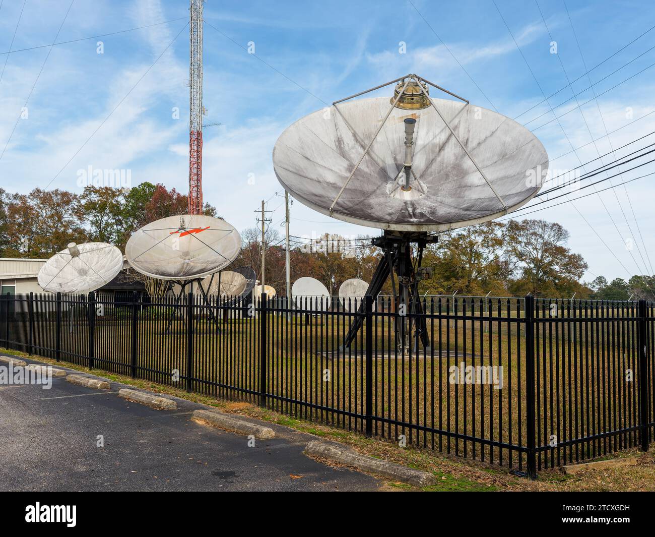 Große Satellitenschalen, die unter einem hohen Fernsehturm oder einer TV-Turmantenne in Montgomery Alabama, USA, aufgereiht sind. Stockfoto