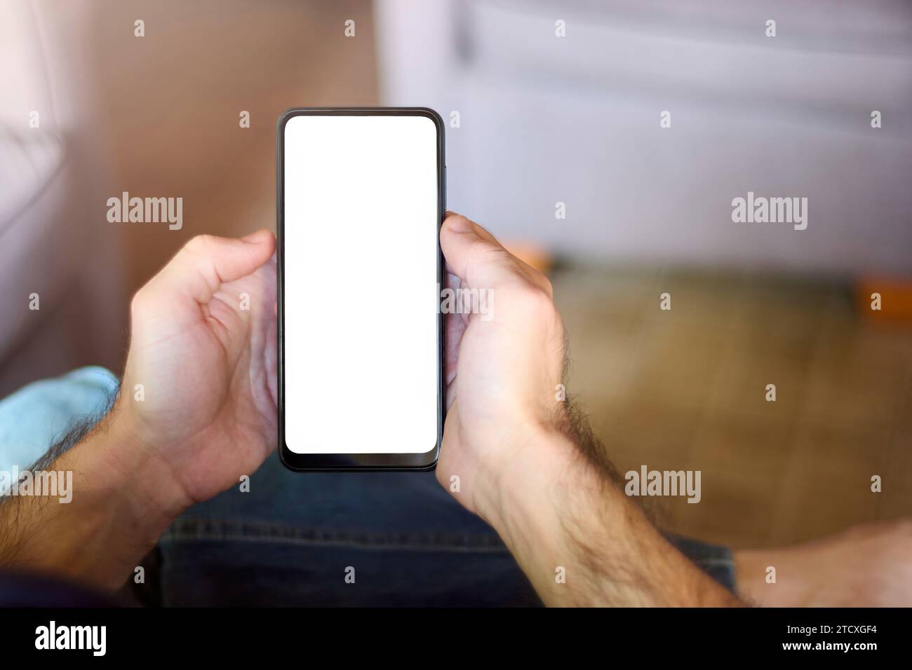 Männliche Hände halten ein schlankes Mobiltelefon mit leerem Bildschirm und bieten ein vielseitiges Modell für personalisierte Designs in Werbung und Kampagnen. Kopie s Stockfoto