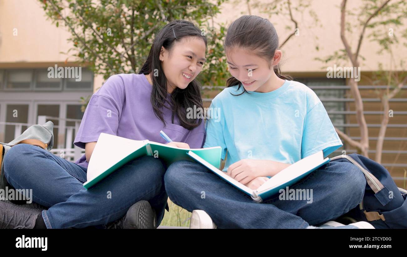 Glückliche asiatische Schülerinnen lernen und diskutieren Hausaufgaben in der Schule Stockfoto