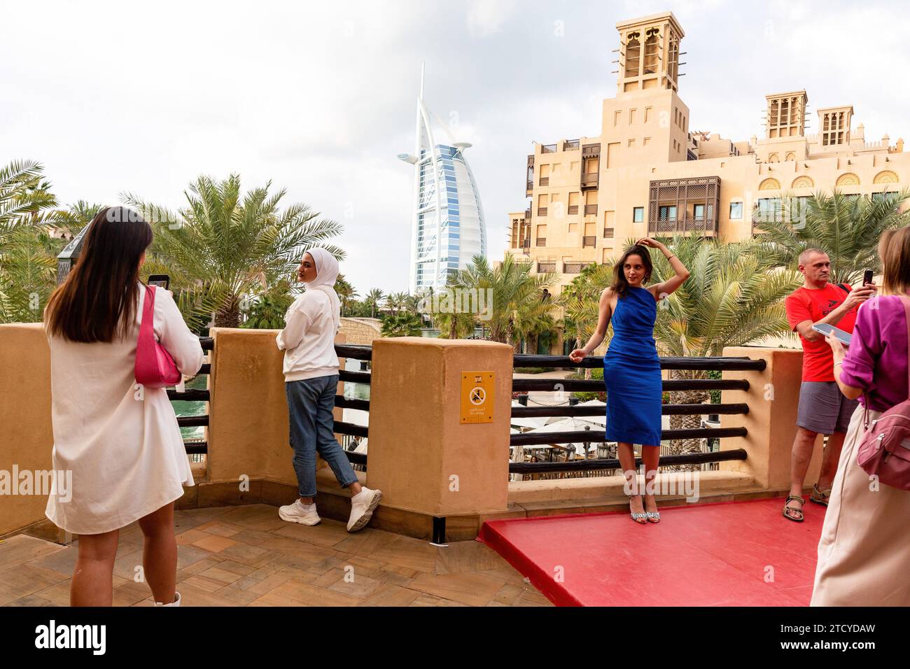 Dubai, Vereinigte Arabische Emirate. Dezember 2023. Touristen machen Fotos mit Burj Al Arab im Hintergrund von Souk Madinat Jumeirah, einem Markt in einem alten Teil der Stadt im Zentrum von Dubai, an einem heißen Abend. Quelle: SOPA Images Limited/Alamy Live News Stockfoto