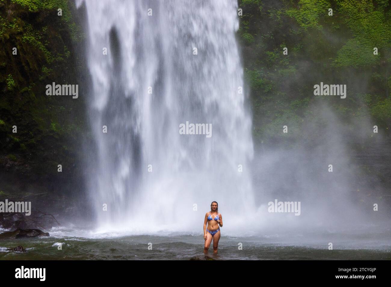 Eine junge Frau im Badeanzug am Nungnung Wasserfall im üppigen tropischen Wald, Bali, Indonesien Stockfoto