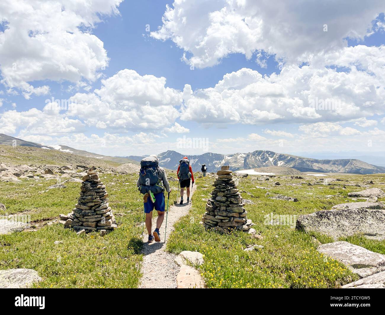 Die Wanderer passieren auf dem North Inlet Trail zwischen Stone cairns, umgeben von der riesigen Schönheit des Rocky Mountain National Park unter einem Himmel flauschiger Wolken. Stockfoto