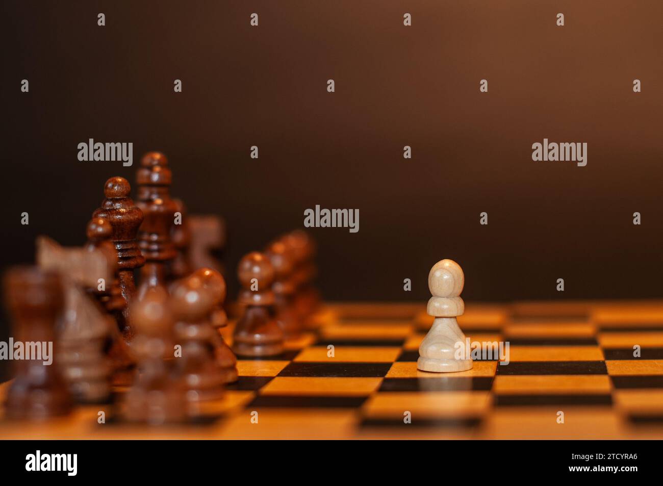 Das Schachspiel beginnt mit der ersten Bewegung des weißen Bauern, der sich zwei Schritte vorwärts bewegt, fotografiert mit einem dunklen Hinterteil Stockfoto