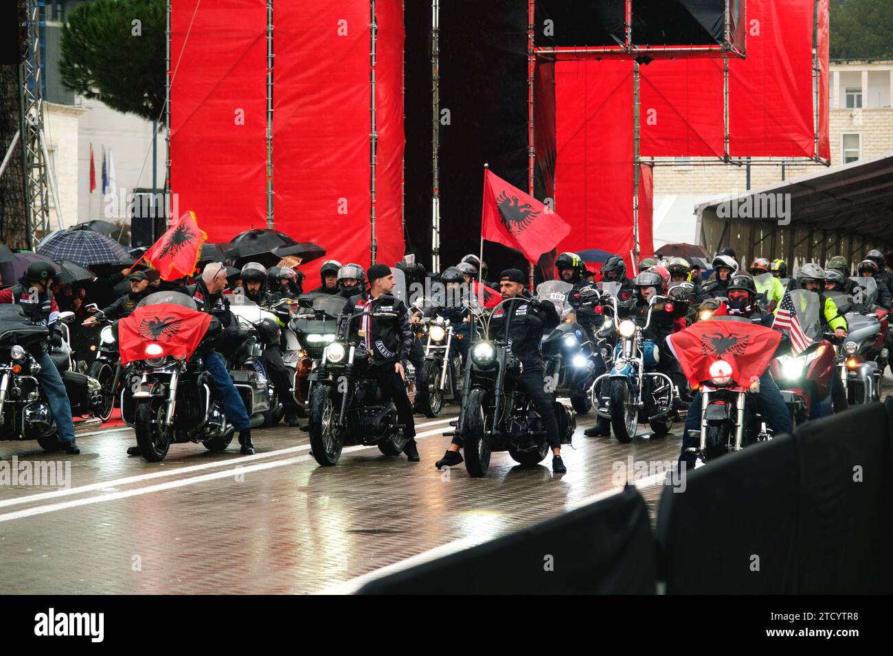 Tirana, Albanien - 28. November 2023: Während eines regnerischen Unabhängigkeitstages zieht eine Motorradgruppe mit albanischer Flagge auf der Avenue der Märtyrer der Nation um Stockfoto