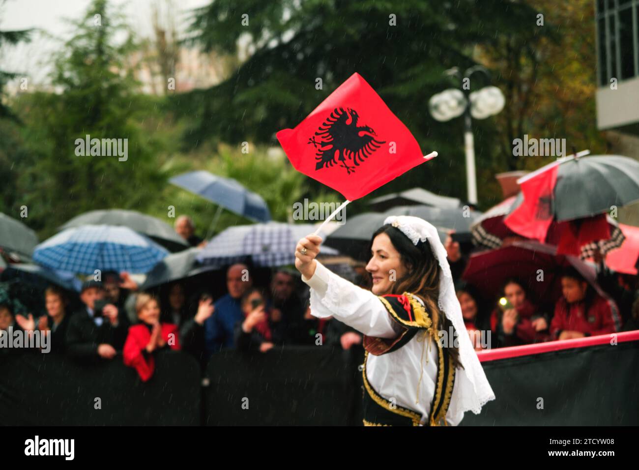 Tirana, Albanien - 28. November 2023: Auf der Avenue der Märtyrer der Nation, in der Nähe von Mutter Teresa Palace, spaziert eine Frau in traditioneller Kleidung jubelnd mit ihr Stockfoto