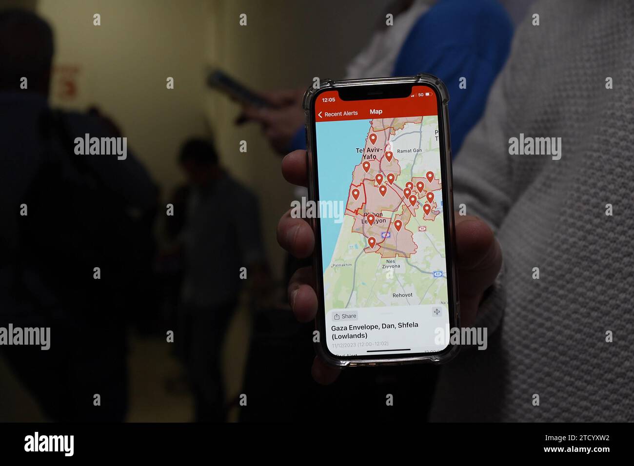 Eine Person zeigt auf seinem Smartphone Standorte, die von Raketenangriffen aus Gaza angegriffen werden, während sie in einem Schutzraum des Ichilov-Krankenhauses Deckung findet, in dem freigelassene Geiseln behandelt und verwundete Soldaten weiterhin empfangen und behandelt werden, während der Krieg mit der Hamas am 11. Dezember 2023 in Tel Aviv fortgesetzt wird. Israel. Seit den Angriffen der Hamas vom 7. Oktober sind mehr als zwei Monate vergangen, die Israels Luft- und Bodenkampagne im Gazastreifen ausgelöst haben. Stockfoto