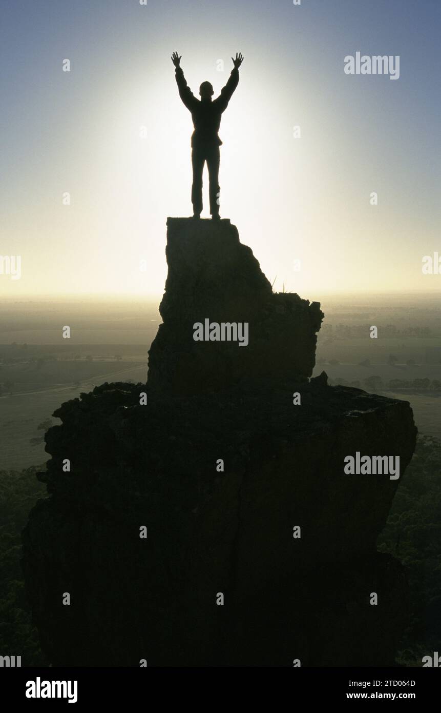 Ein Mädchen steht auf einem Gipfel bei Sonnenaufgang. Stockfoto