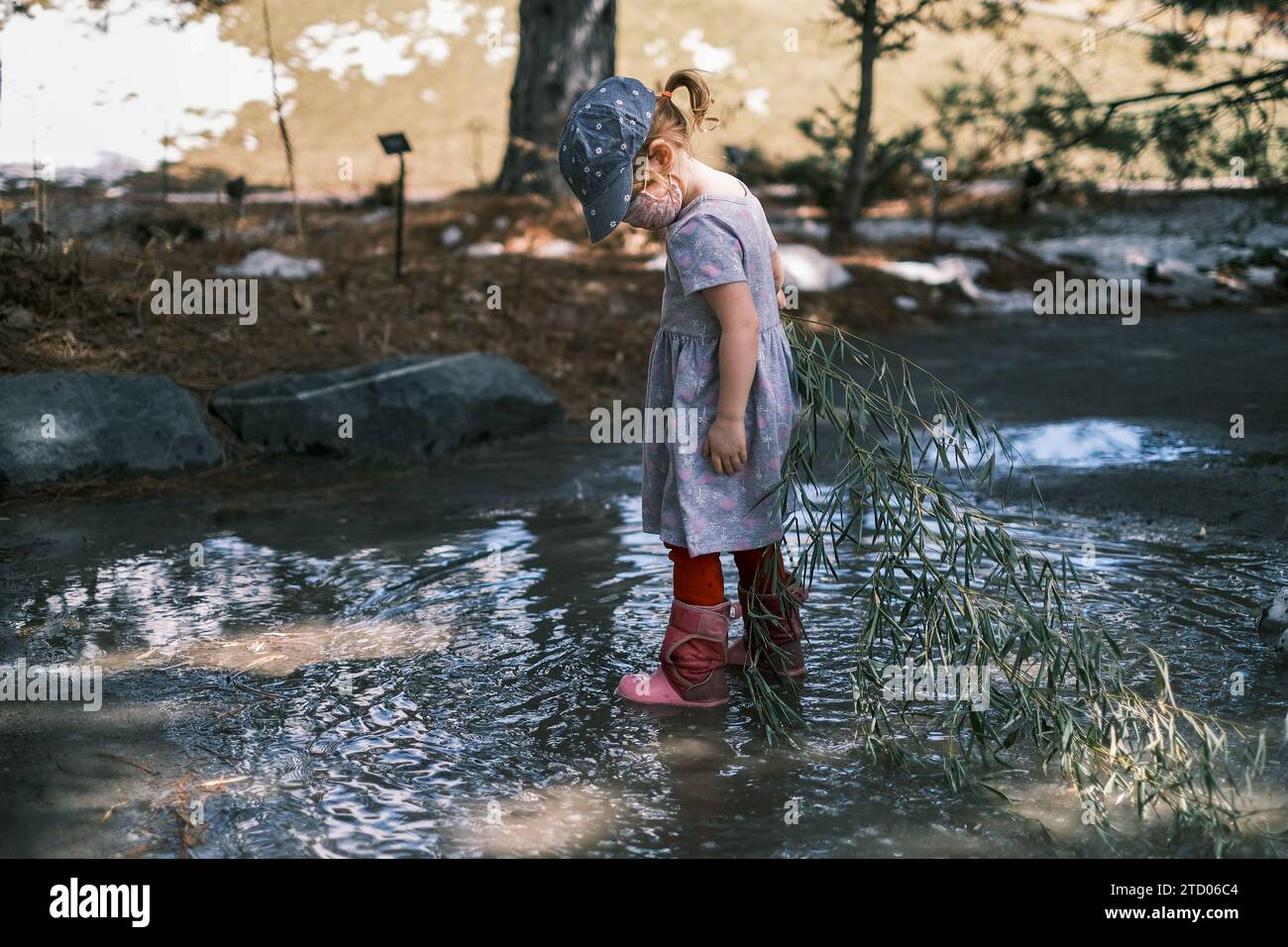 Kind spielt in einer schlammigen Pfütze an einem nassen Tag Stockfoto