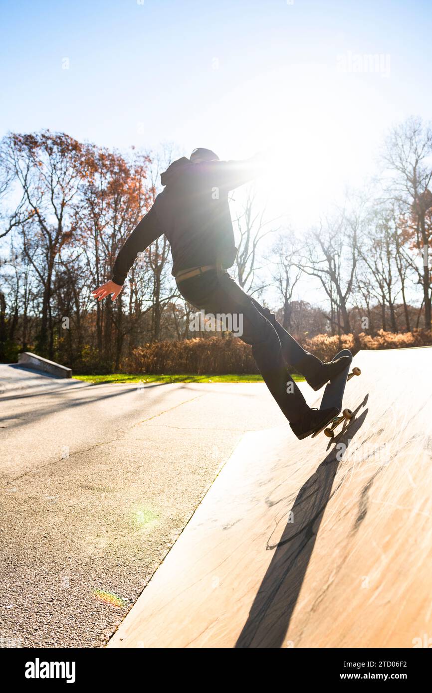 Solo-Mann-Skateboarden auf einer Skatepark-Rampe im Herbst mit Linsenflackern Stockfoto