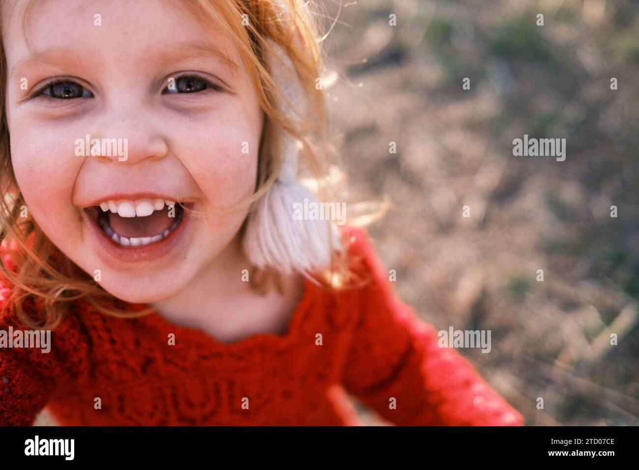 Fröhliches Kleinkind lächelt und blickt mit unschuldigen Augen in die Kamera Stockfoto