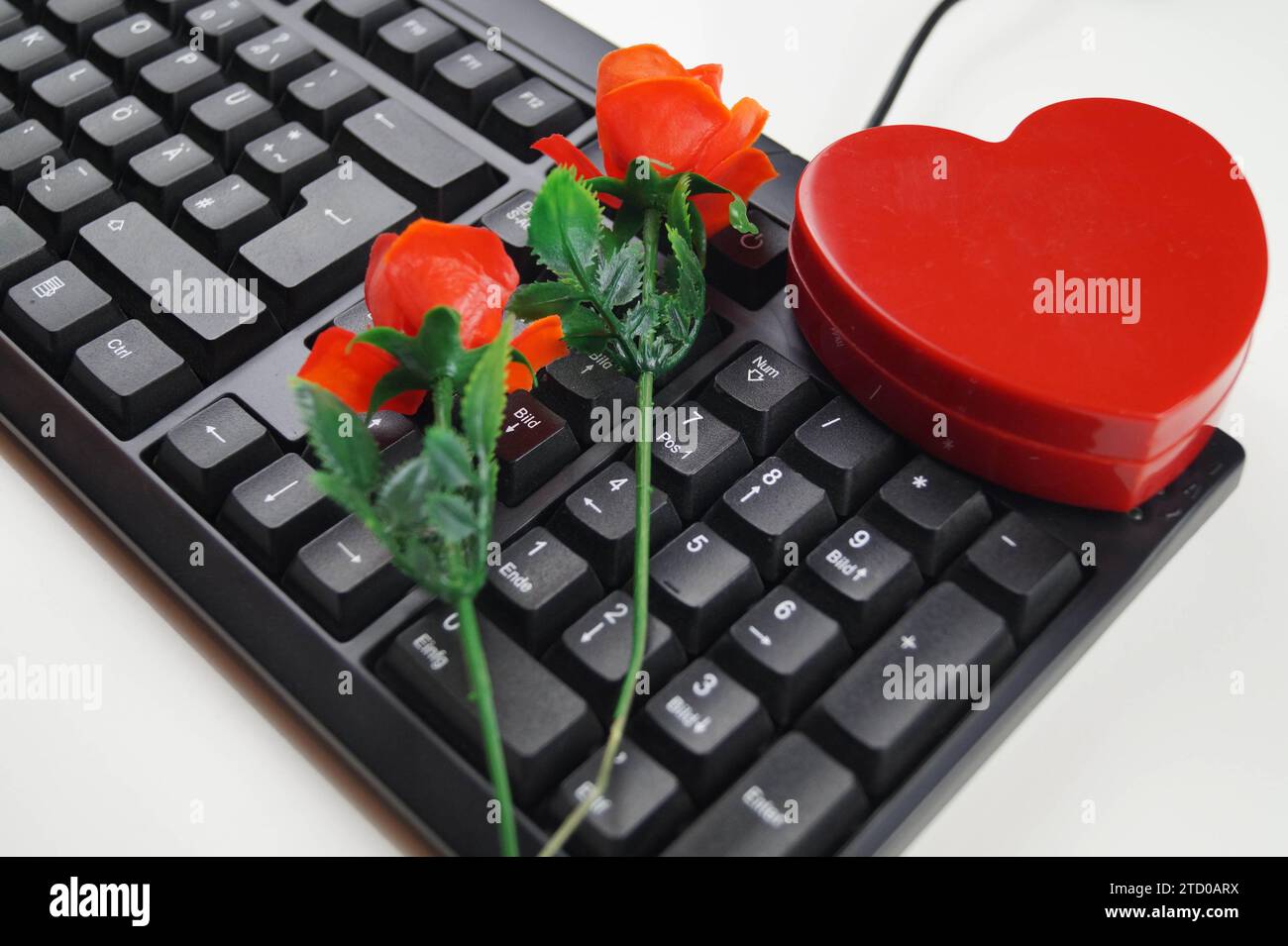 Rotes Herz und rote Rosen mit Computertastatur, symbolisches Bild der Liebe online Stockfoto