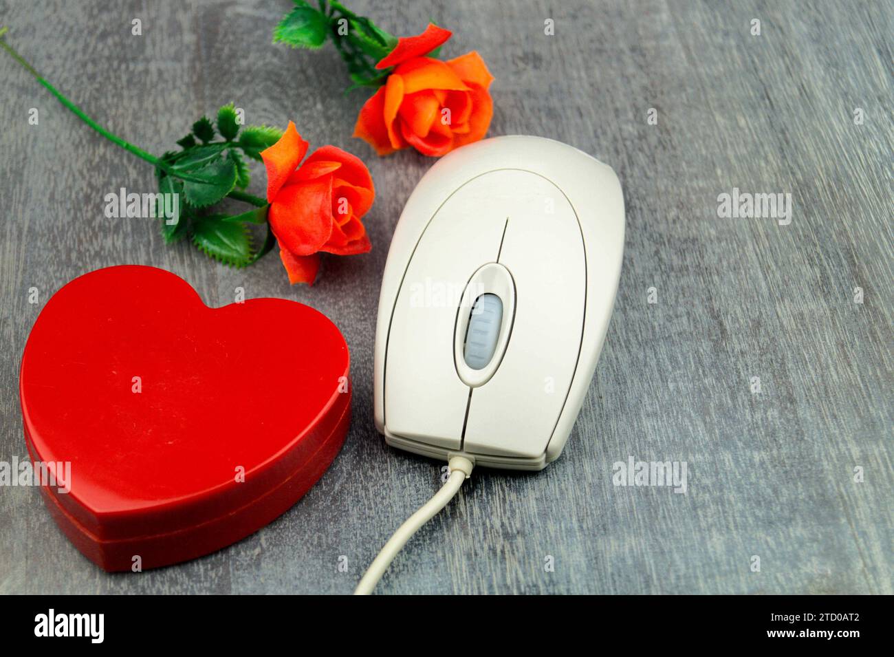 Rotes Herz und rote Rosen mit Computermaus, symbolisches Bild der Liebe online Stockfoto