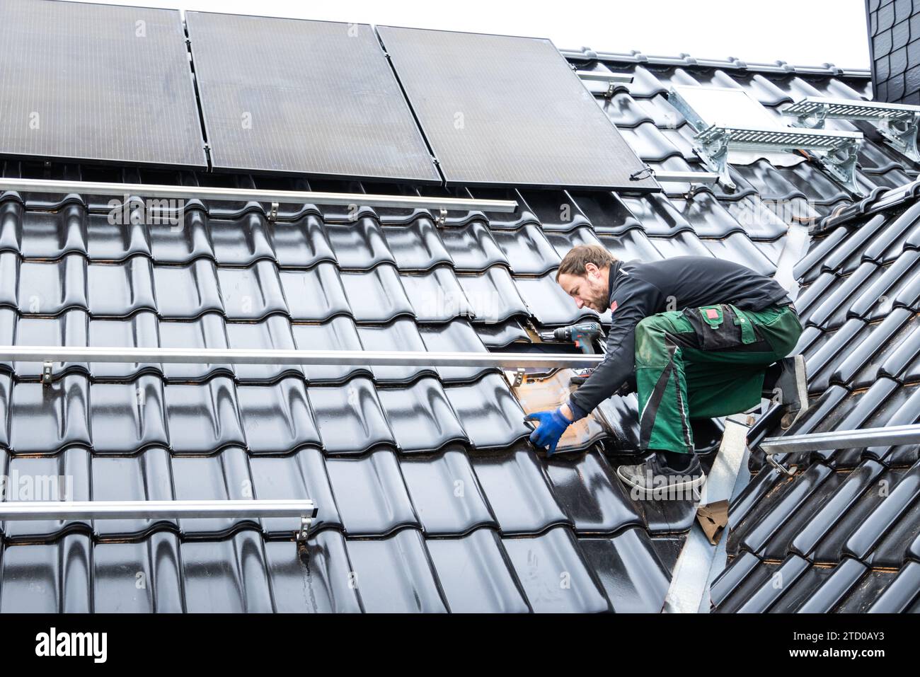 Techniker, der eine Solar Panel-Anordnung auf dem Dach eines Hauses installiert Stockfoto
