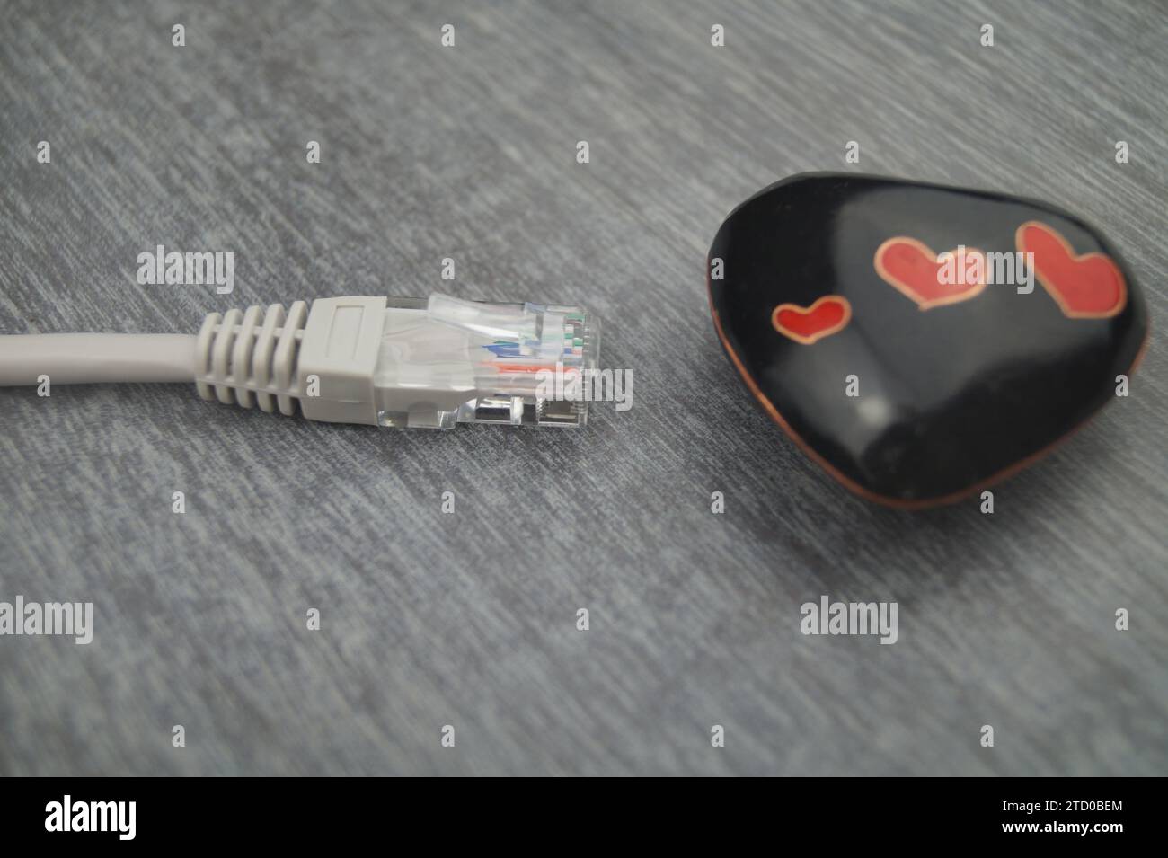 Herz mit grauem Internetkabel, symbolisches Bild der Liebe online Stockfoto