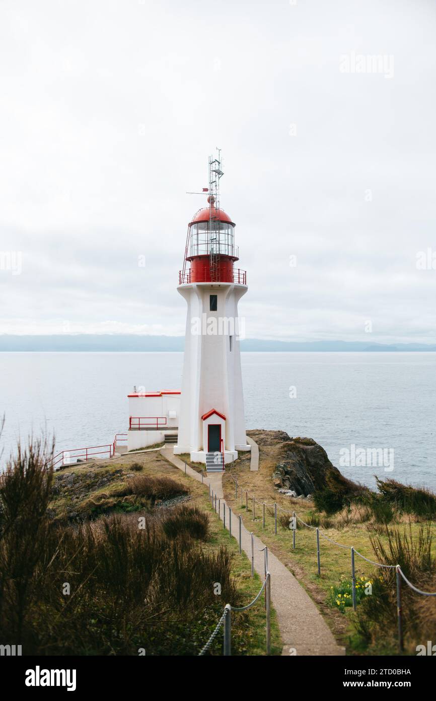 Ein ruhiger Blick auf einen traditionellen weißen und roten Sheringham Point Lighthouse auf Vancouver Island, mit Blick auf das ruhige Wasser des Pazifischen Ozeans und Stockfoto