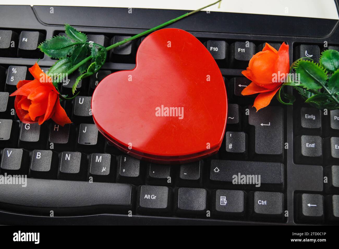 Rotes Herz und rote Rosen mit Computertastatur, symbolisches Bild der Liebe online Stockfoto