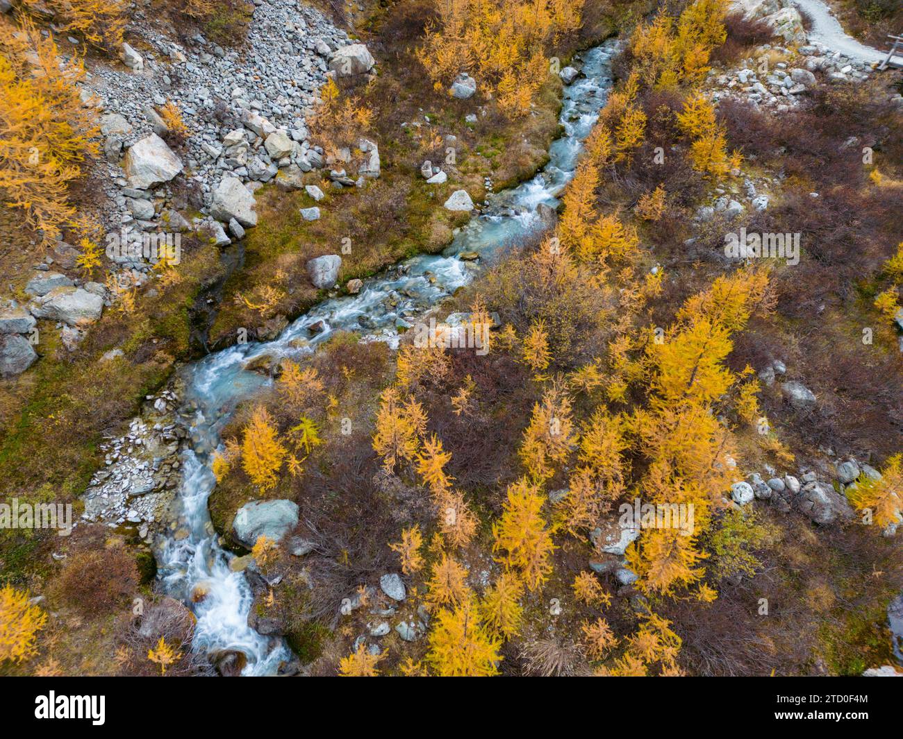 Blick aus der Vogelperspektive auf einen sich schlängelnden Fluss, umgeben von herbstlichen Bäumen in einem bergigen Gelände. Stockfoto