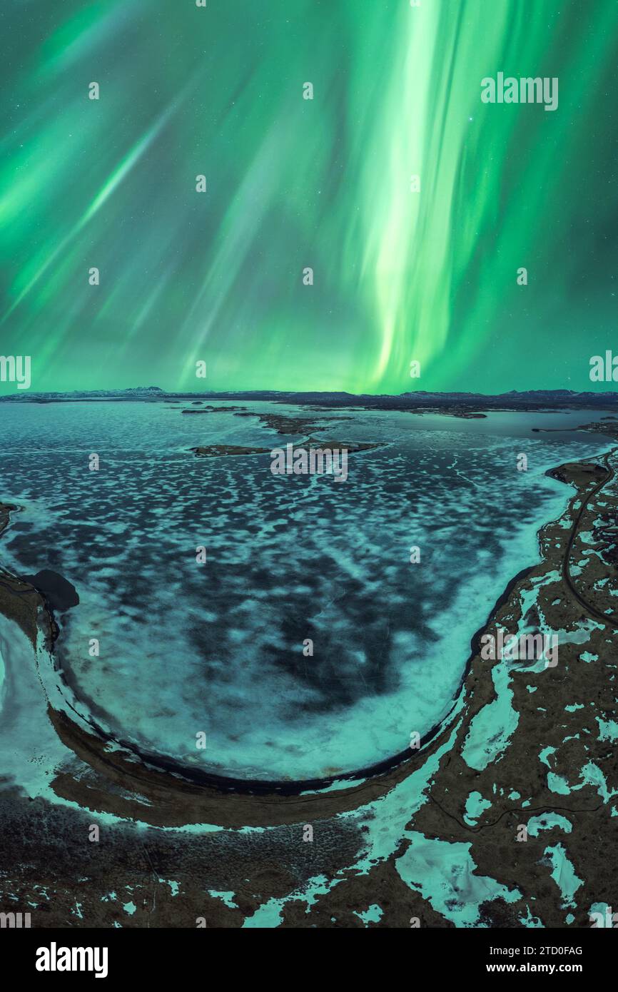 Spektakuläre Aussicht auf die Nordlichter, die über einer verschneiten Flussbiegung in der ruhigen isländischen Wildnis tanzen. Stockfoto