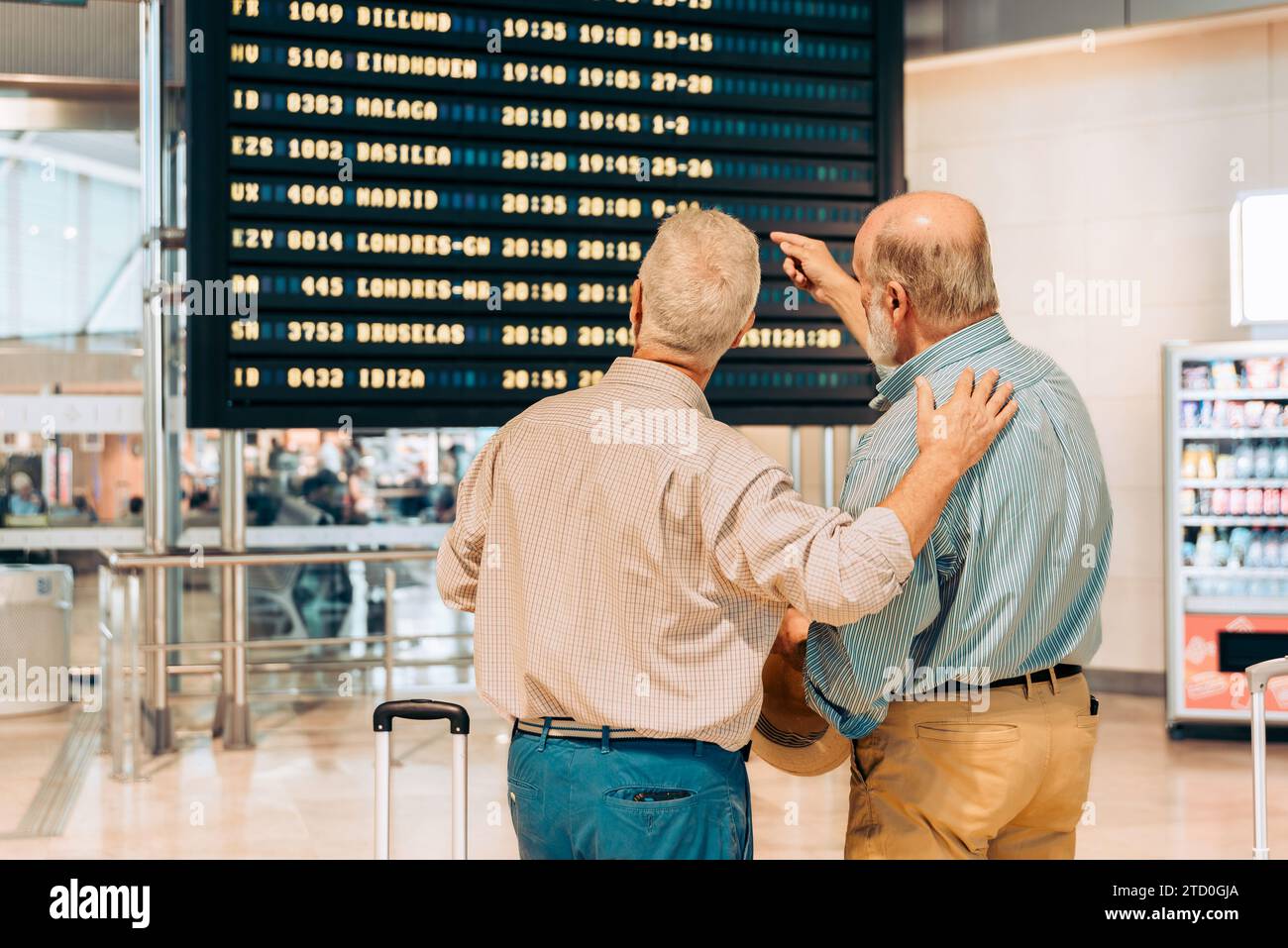 Rückansicht von anonymen älteren männlichen Touristen in ungezwungener Kleidung, die auf der Abflugplantafel am zeitgenössischen Flughafen während des Urlaubs schauen Stockfoto