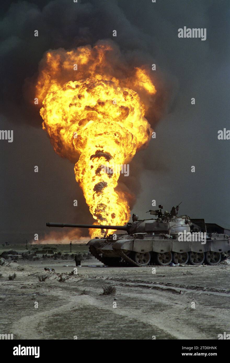 Erster Golfkrieg: 7. März 1991 ein Ölbrunnen brennt außer Kontrolle über einen verlassenen irakischen T55-Panzer im Burgan-Ölfeld südlich von Kuwait City. Stockfoto