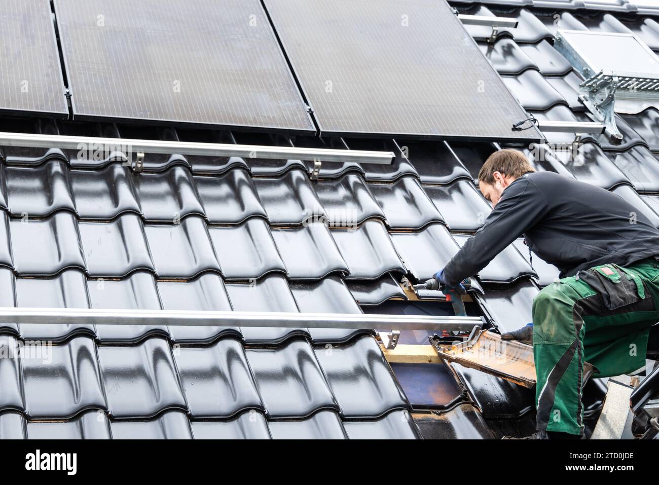 Techniker, der an der Montagestruktur für Solarpaneele auf dem Dach eines Hauses arbeitet Stockfoto