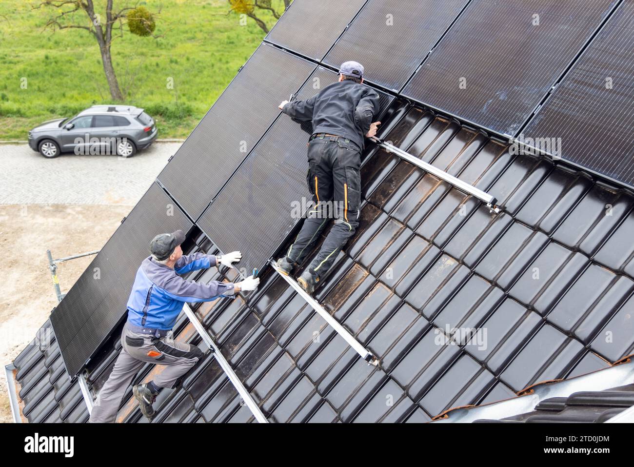 Zwei Techniker arbeiten an der Installation von Solarpaneelen auf dem Dach eines Hauses Stockfoto