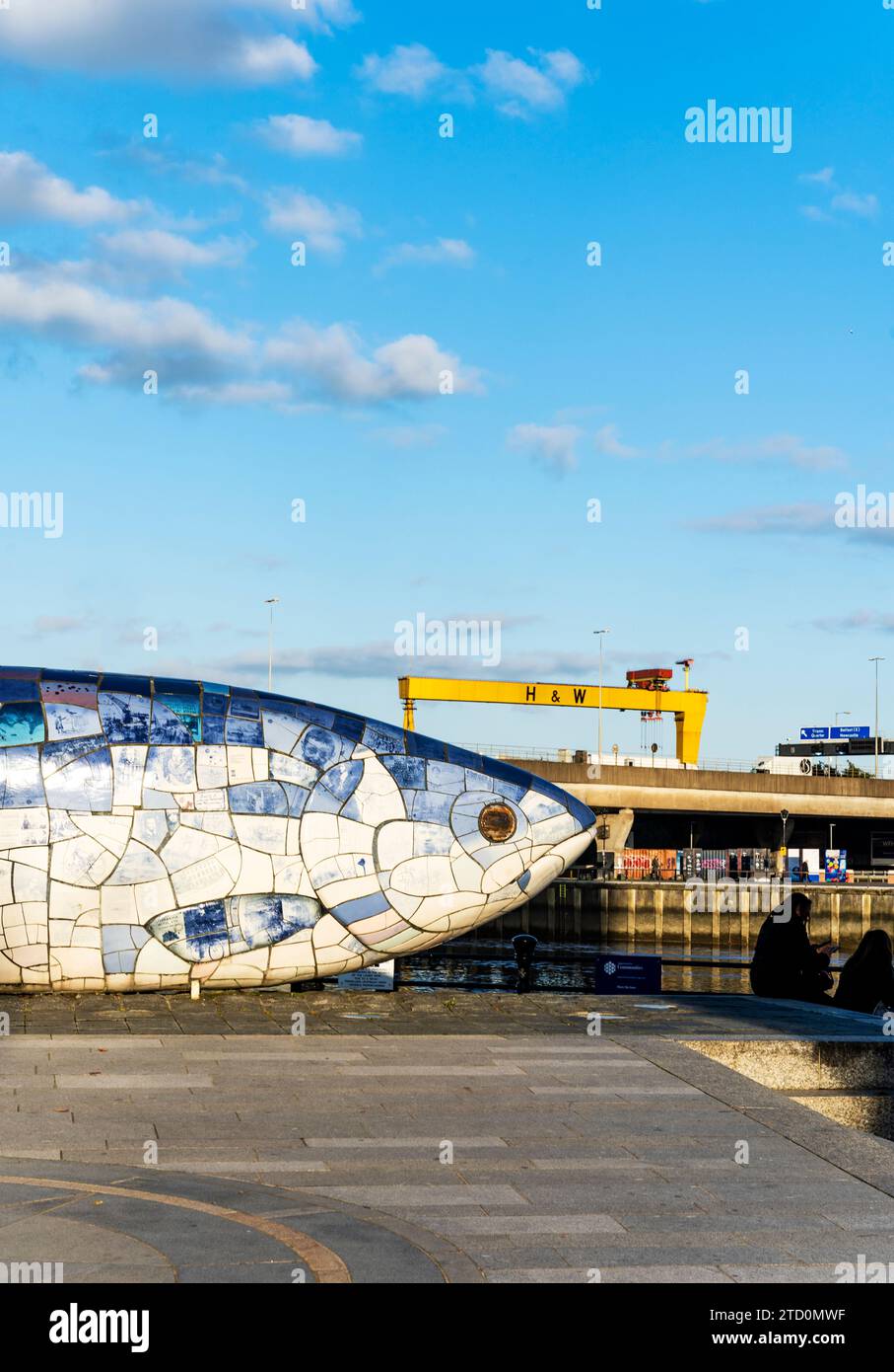 Skulptur Salmon of Knowledge oder Big Fish mit zwei gelben Schiffbau-Portalkranen Samson und Goliath entlang des Flusses Lagan, Belfast, Nordirland. Stockfoto