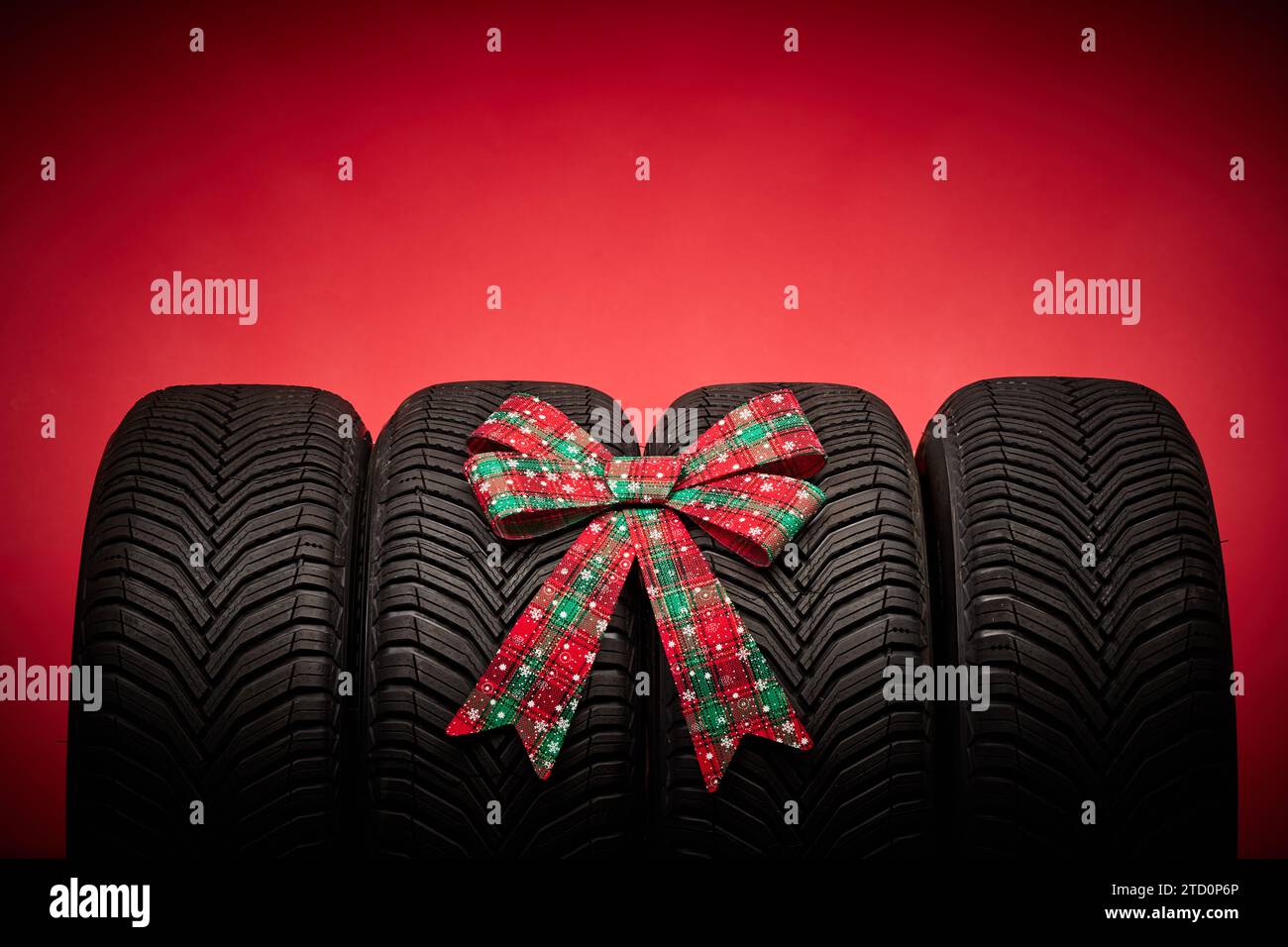 Autoreifen, neue Reifen, Winterräder isoliert auf rotem weihnachtshintergrund mit Schleifenband Geschenk. Stockfoto