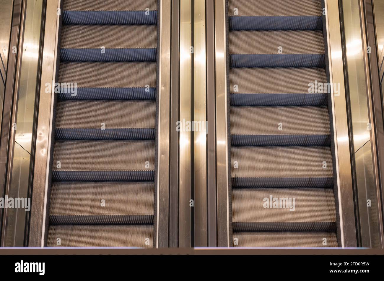 Ein Paar Rolltreppen, die von einem Bahnhof zu einem Flughafenterminal führen, von oben gesehen. Stockfoto