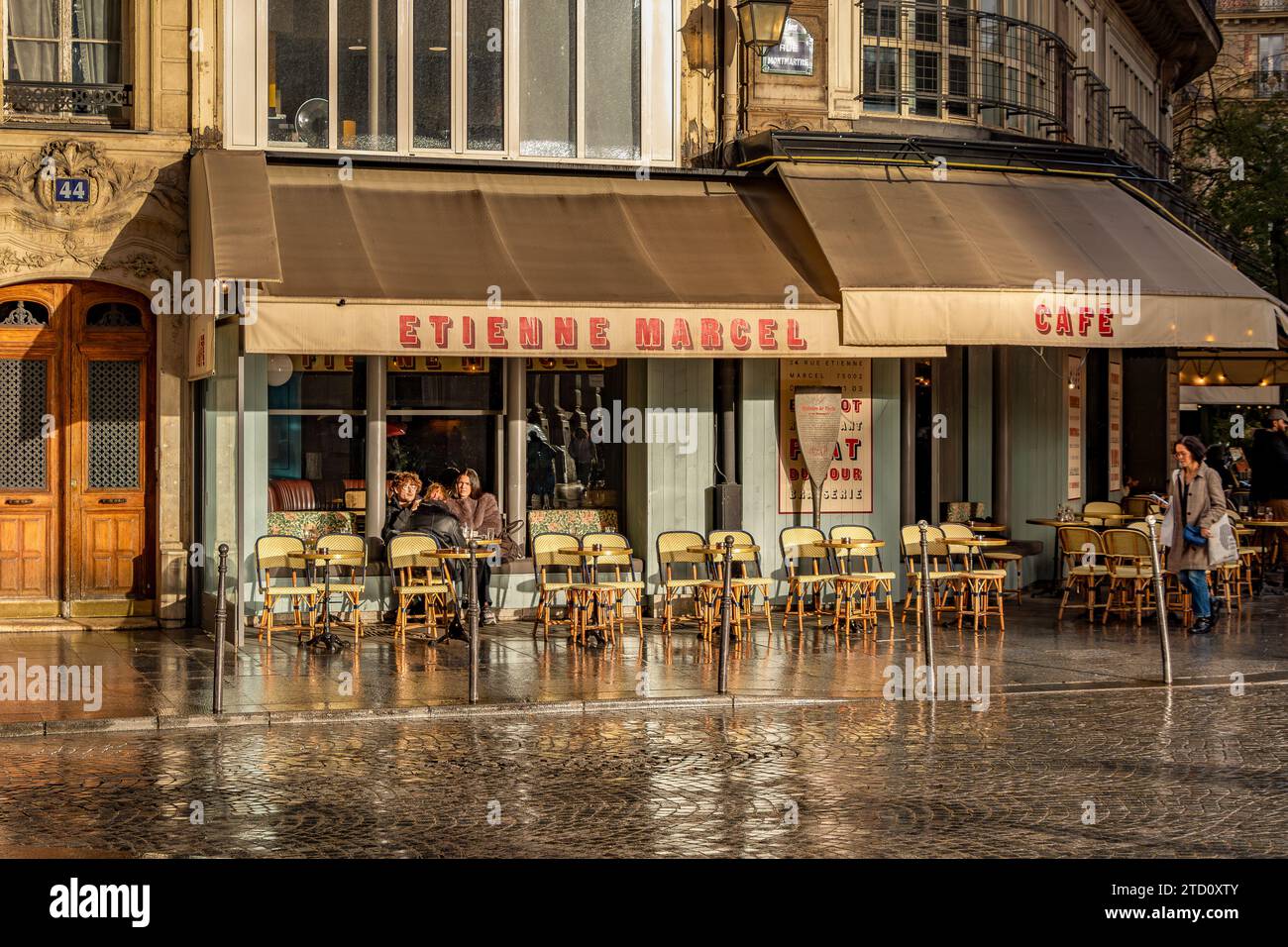 Sonnenlicht reflektiert von der nassen Straße vor dem Café Etienne Marcel, einer Brasserie in der 34 Rue Etienne Marcel im 2. Arrondissement von Paris Stockfoto