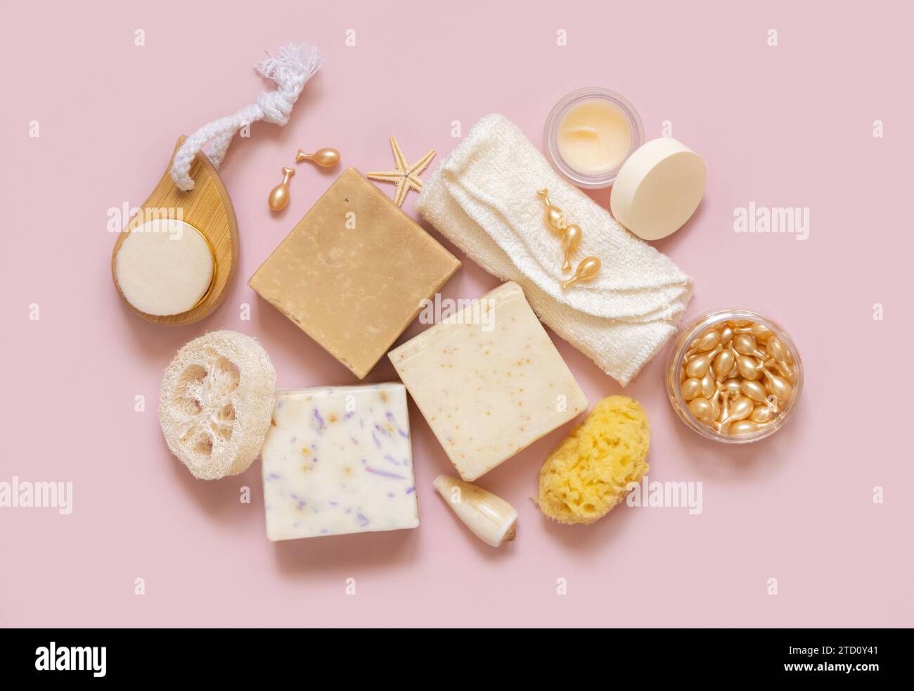 Beige Seifenriegel, Muscheln, natürliche Schwämme und Handtücher mit hellrosa Draufsicht. Pflanzliche Produkte für Gesichts- und Körperpflege. Mit Bio-Naturhautpflege p Stockfoto