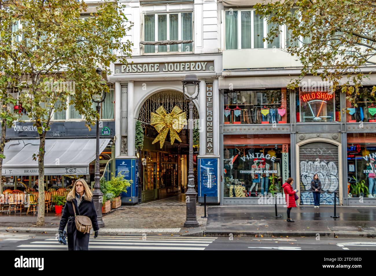 Zwei Frauen und ein Hund überqueren die Straße am Eingang zur Passage Jouffroy am Boulevard Montmartre, einer der beliebtesten überdachten Gänge in Paris Stockfoto