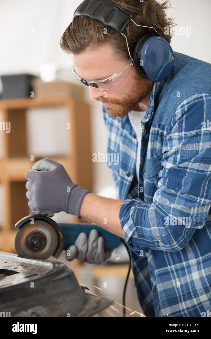 Ein junger Baumeister sägt ein Brett mit einer Kreissäge Stockfoto