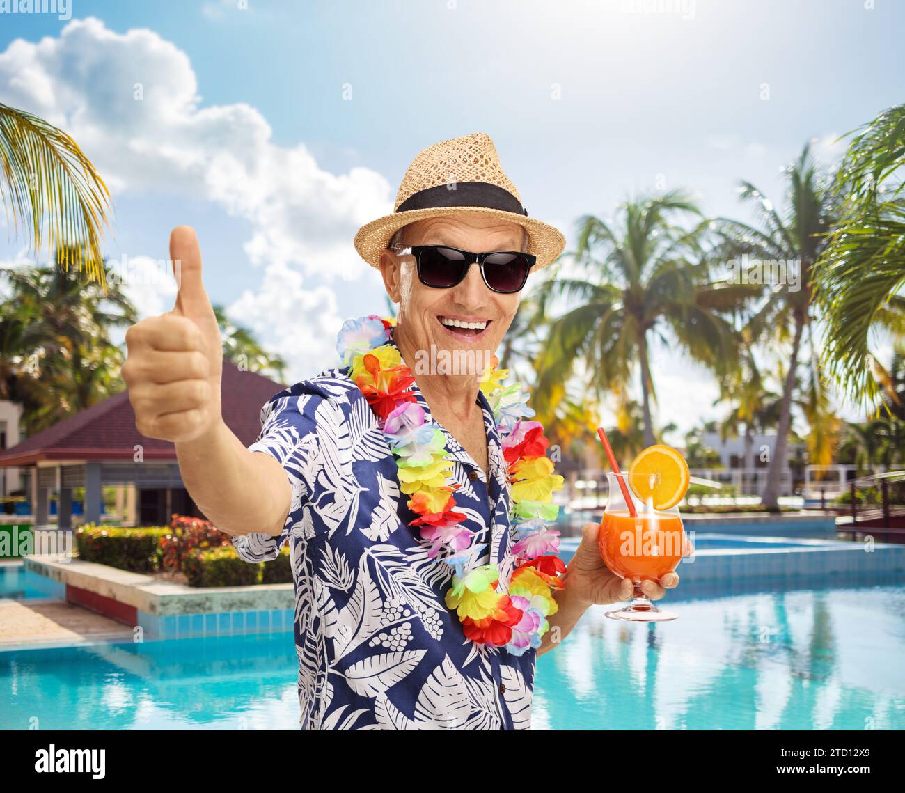 Fröhlicher Seniorenreisender mit einem Cocktail und einem Daumen nach oben am Pool Stockfoto