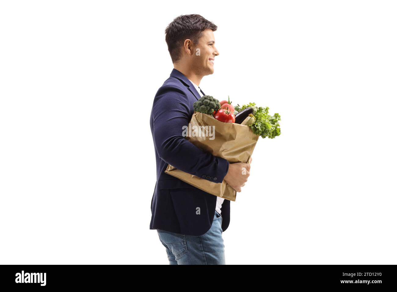 Profilaufnahme eines Mannes, der eine Papiertüte mit Lebensmitteln auf weißem Hintergrund trägt Stockfoto