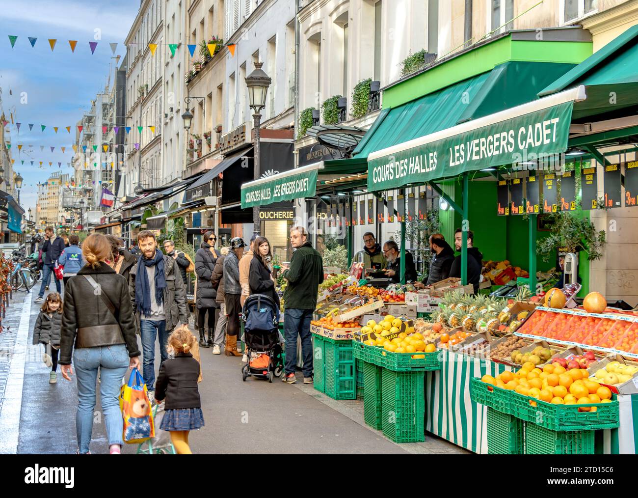 Eine junge Familie, die in Paris shoppt, geht vorbei an Les Vergers Cadet, einem Obst- und Gemüseladen in der Rue Cadet im 9. Arrondissement von Paris, Frankreich Stockfoto