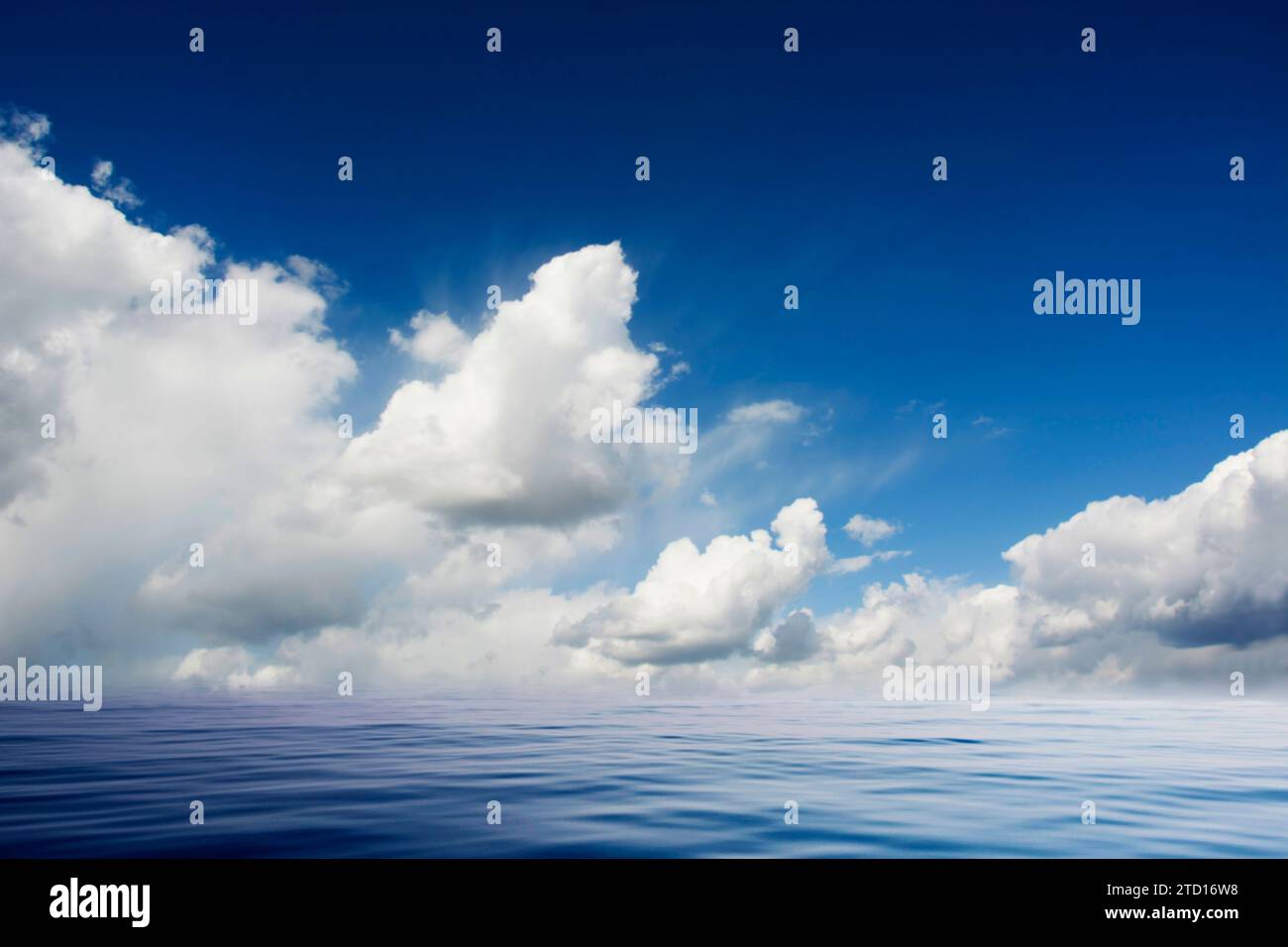 Ruhiges Meer und blauer Himmel mit geschwollenen weißen Wolken Stockfoto