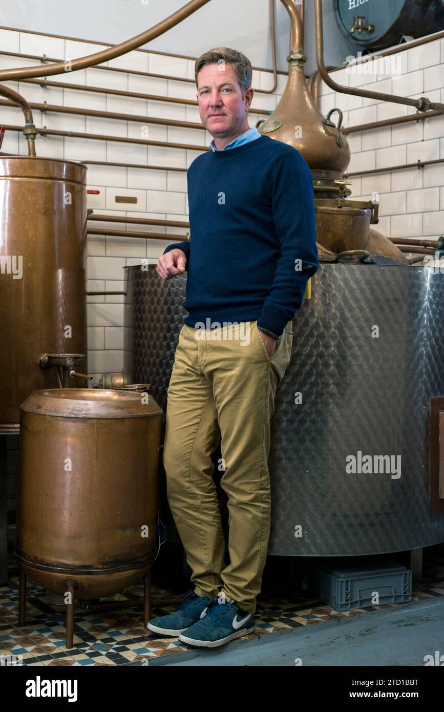 Ein männlicher Kleinunternehmer steht mit seiner Gin-Ausrüstung in einer handwerklichen Destillerie. Stockfoto