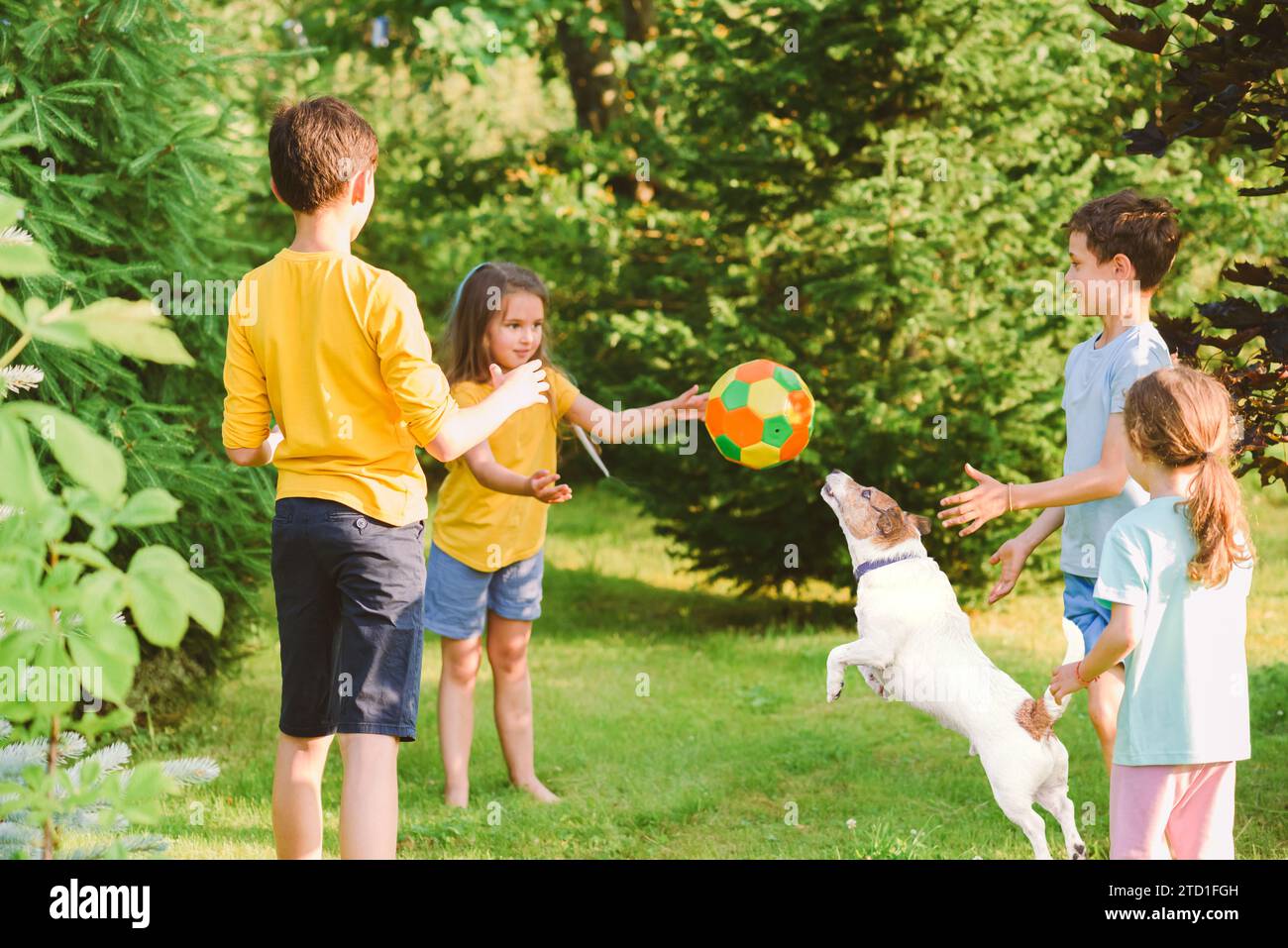 Eine Gruppe von Kindern wirft und fängt einen Ball, während sie mit einem Hund das Spiel „Affe in der Mitte“ spielen Stockfoto