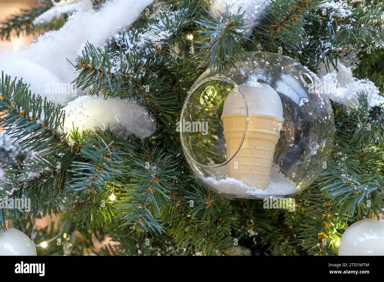 Eis in einem Waffelbecher in einer durchsichtigen Kugel auf dem Weihnachtsbaum. Neujahrskonzept. Stockfoto