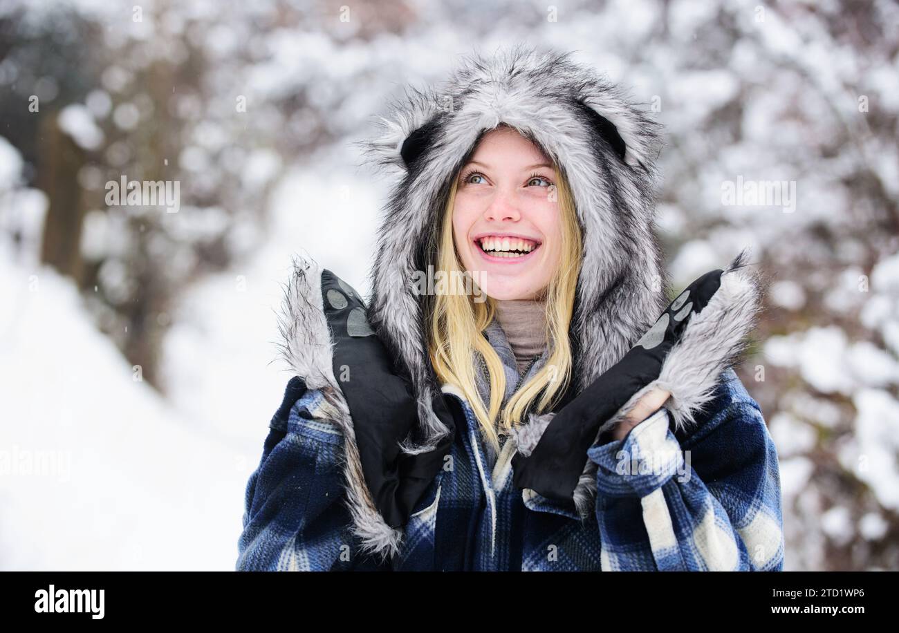 Glückliche Frau, die den schneebedeckten Wintertag genießt. Weihnachtsmädchen in kariertem Mantel, Pelzmütze und Fäustlingen. Modemädchen im Winter. Schöne Frau in warm Stockfoto
