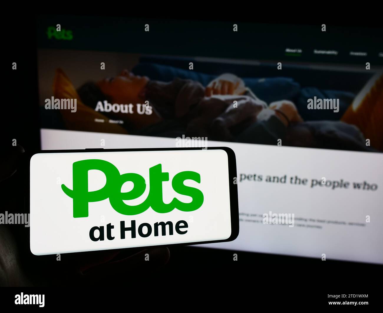 Person mit Smartphone und Logo des britischen Einzelhandelsunternehmens Pets at Home Group vor der Website. Schwerpunkt auf dem Display des Telefons. Stockfoto