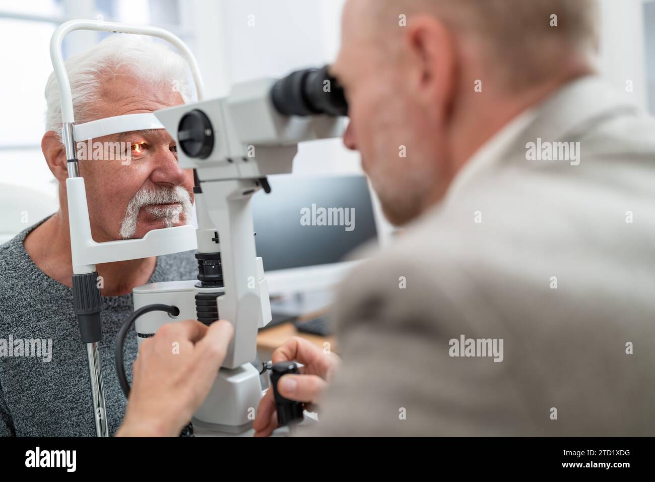 Optometrist mit einer Spaltlampe, um das Auge eines Seniorenmannes in der Klinik zu untersuchen. Nahaufnahme. Gesundheitswesen und Medizinkonzept Stockfoto