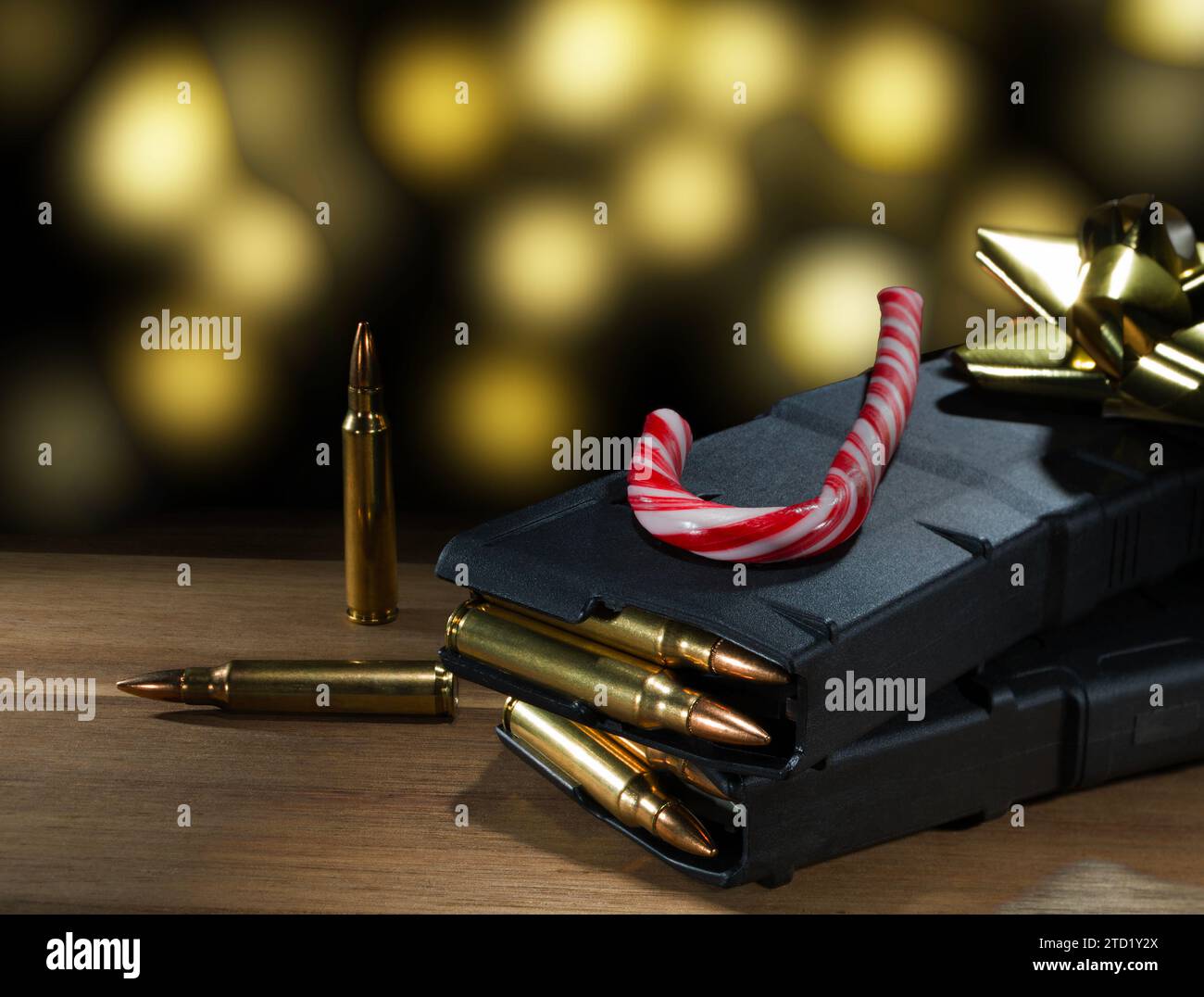 Gelbe Weihnachtslichter leuchten in einem Strümpfe mit AR-15-Magazinen und Munition aus Polymer mit einem Zuckerrohr und einer goldenen Schleife darüber. Stockfoto