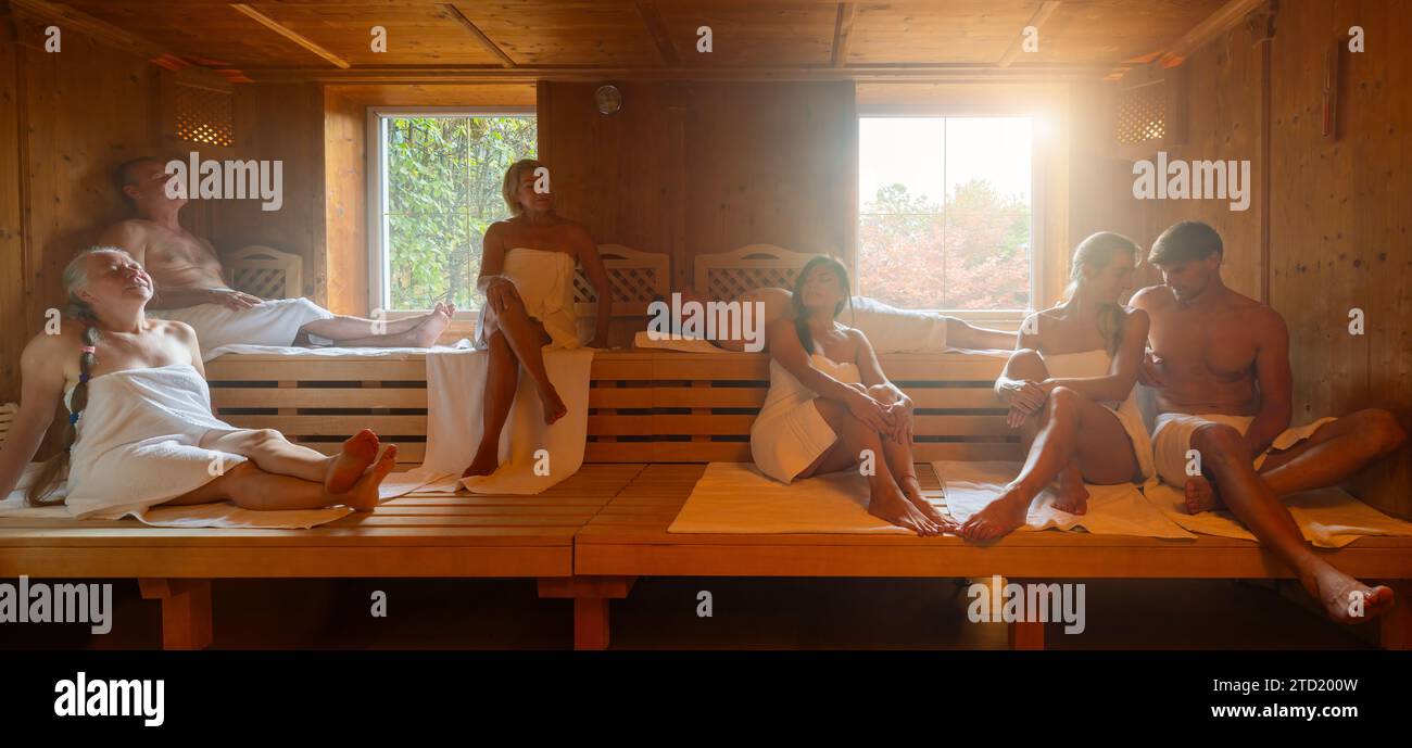 Gruppe von Menschen verschiedener Altersgruppen, die sich gemeinsam in der heißen finnischen Sauna entspannen. Dramatisches Licht mit Dampfbad, Spa und Wellness-Konzept. Stockfoto