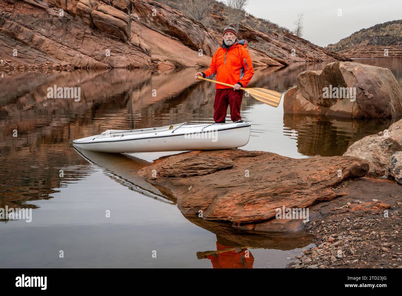 Älterer männlicher Paddler mit einem überdachten Expeditionskanu mit einem Holzpaddel an einem felsigen Ufer des Horsetooth Reservoir in der Nähe von Fort Collins, Colorado Stockfoto