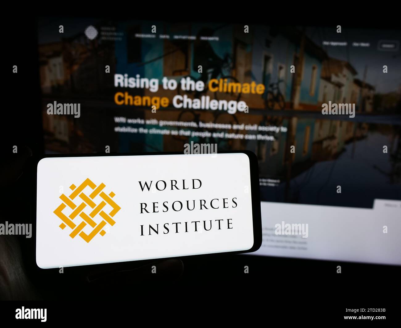 Person mit Smartphone und Logo der Forschungsorganisation World Resources Institute (WRI) vor der Website. Schwerpunkt auf dem Display des Telefons. Stockfoto