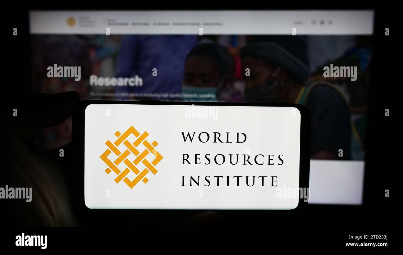 Person mit Handy und Logo der Forschungsorganisation World Resources Institute (WRI) vor der Webseite. Schwerpunkt auf dem Display des Telefons. Stockfoto