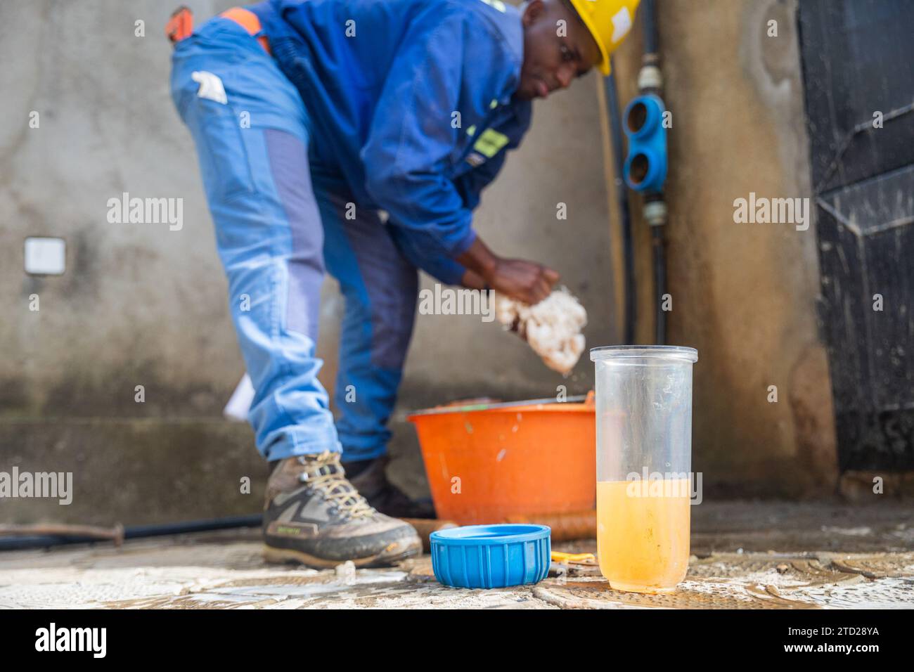 Junger afrikanischer Arbeiter, der die Behälter der Filter wäscht. Wasserfiltrationskonzept. Stockfoto